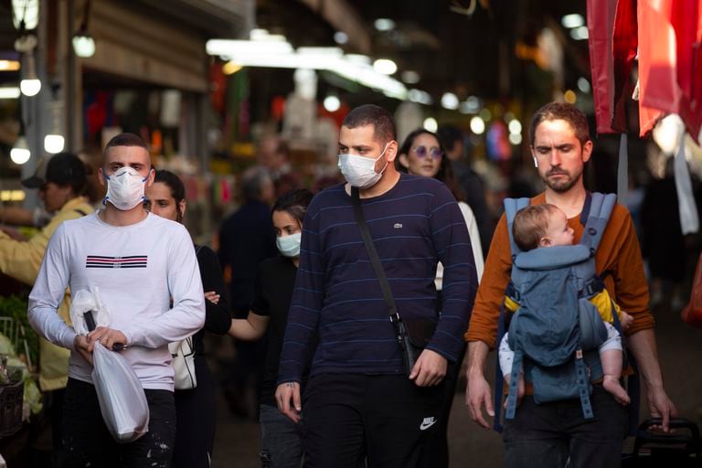 Un grupo de vecinos de Tel Aviv, algunos con mascarillas como protección contra la Covid-19, pasean por las calles de la ciudad israelí.