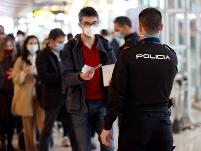Un agente de la policía controla el paso de viajeros en el aeropuerto de Barajas, en Madrid, el 19 de marzo.