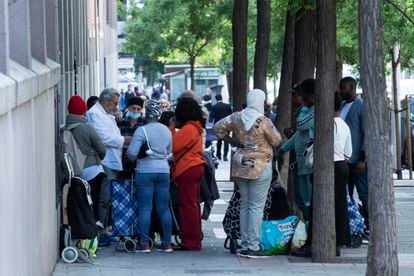 Varias personas esperando para recoger alimentos en la Fundación Karibu (Madrid).