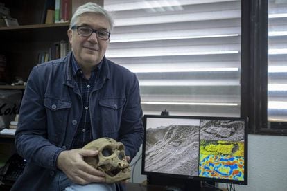 Fernando Muñiz, uno de los investigadores de las huellas de los neandertales, sostiene la reproducción de un cráneo de estos homínidos mientras muestra la huella hallada en Gibraltar.