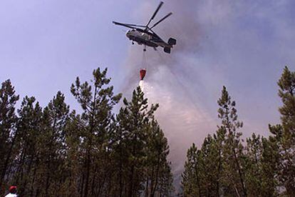 Un helicóptero lanza agua sobre la zona incendiada en la localidad de Almonaster la Real (Huelva).