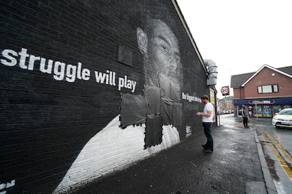 Un operario tapaba este lunes con cinta negra los insultos escritos en el mural de homenaje al jugador Marcus Rashford, en Mánchester (Inglaterra).