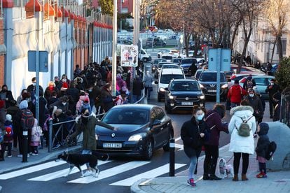 Niños de infantil y primaria entrando a clase entre vehículos en el colegio Sagrado Corazón Padres Capuchinos de Madrid, con la A-42 al fondo. 