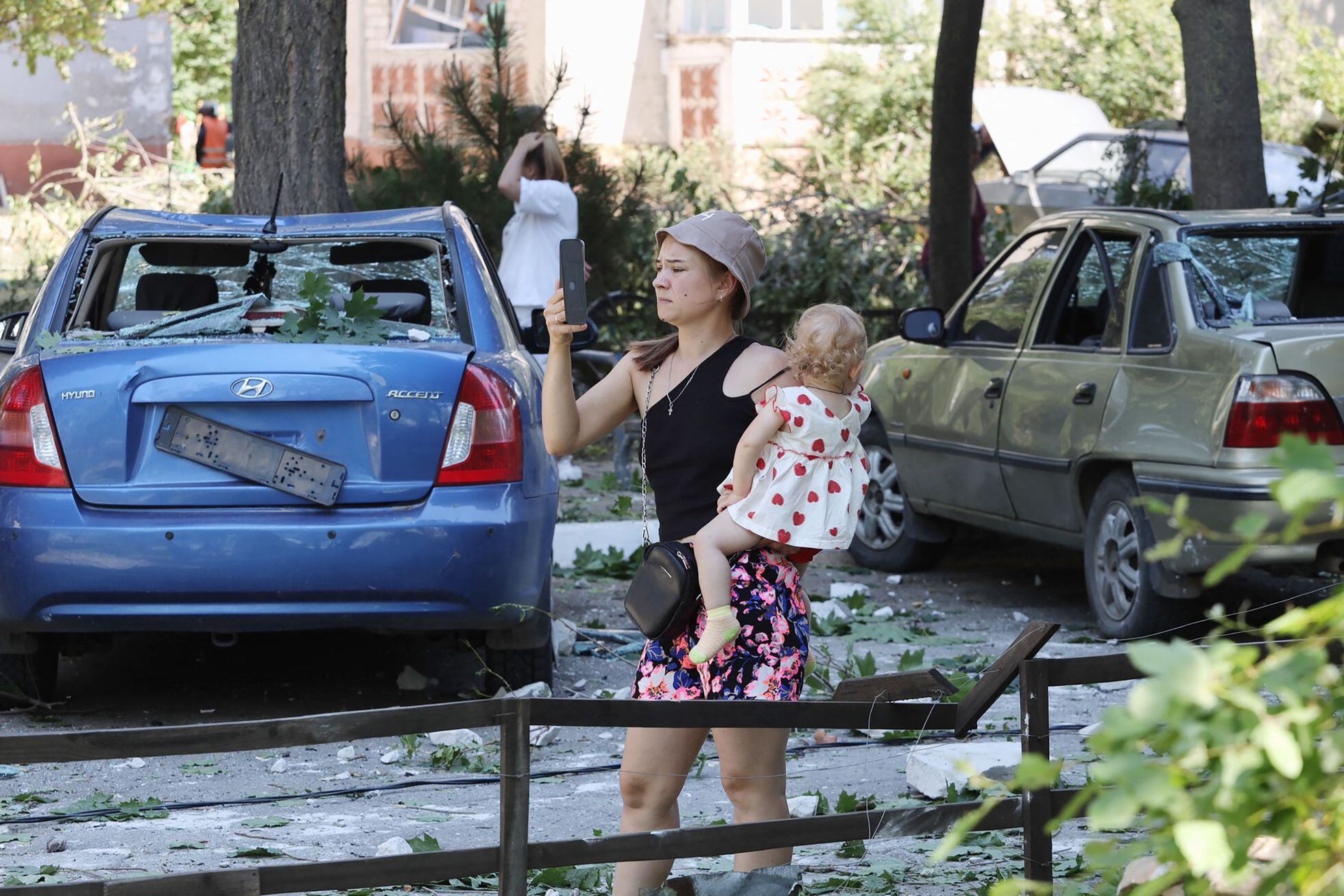Una mujer, con un niño en brazos, toma una foto de un edificio destruido en la ciudad ucrania de Serhiivka, cerca de Odesa.