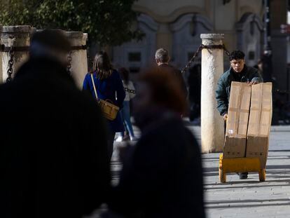 Un joven traslada mercancía con una carretilla, en Sevilla.