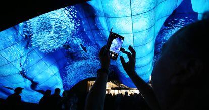 Un hombre saca una foto bajo una pantalla curva OLED de LG Electronics durante el CES 2020