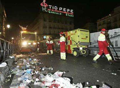 Personal del servicio municipal de limpieza recogen la basura acumulada ayer en la Puerta del Sol.