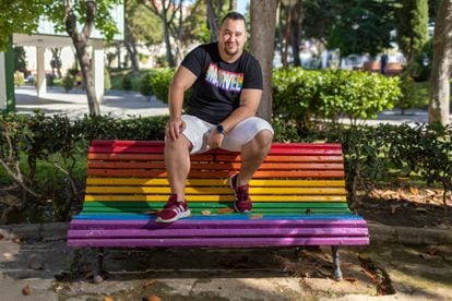 Alejandro Mikael, en un banco con los colores LGTBI en San Fernando, Cádiz. 