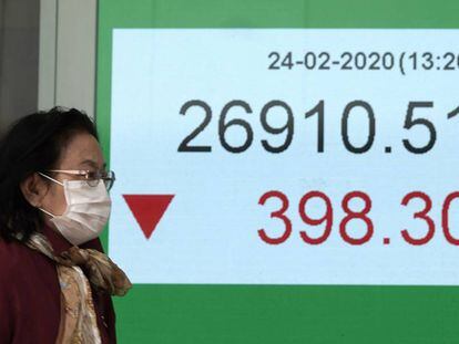 Una mujer pasa ante una pantalla de un índice bursátil en Hong Kong.