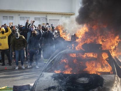 Varios trabajadores protestan junto a un coche ardiendo en las protestas a la entrada de la sede de Navantia en Cádiz.