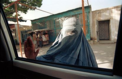 Una mendiga vestida con un burka detiene un coche en busca de dinero en las calles de Kabul, Afganistán, en mayo de 2000.