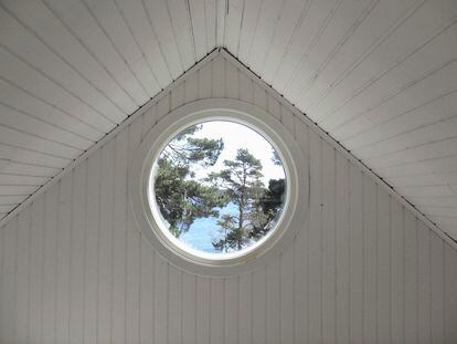 Un ático con una ventana redonda con vistas al mar.