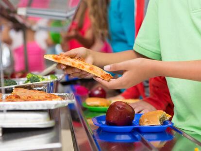 un niño elige pizza en el comedor escolar.