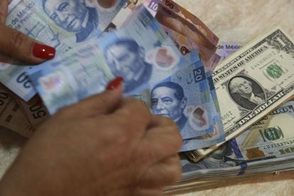Una trabajadora cuenta billetes de pesos mexicanos encima de dólares estadounidenses, en una casa de cambio en México.
