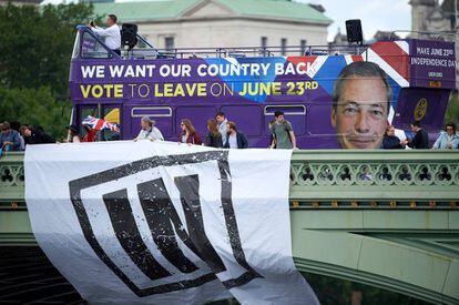 Un autobús con publicidad a favor del 'Brexit' pasa por detrás de unos partidarios de la permanencia.
