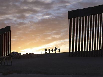 Un par de familias migrantes provenientes de Brasil pasan por un hueco del muro fronterizo para alcanzar Estados Unidos tras cruzar México, en Yuma, Arizona, EE UU.