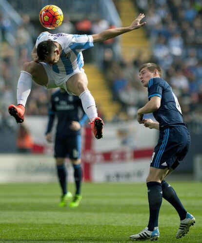 El jugador brasileño del Málaga, Charles, intenta controlar la pelota con la cabeza ante la mirada del jugador madridista Toni Kroos.