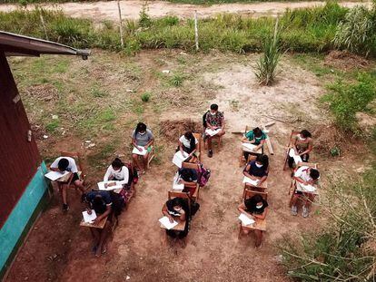 Alumnos de la Amazonía peruana escuchan la clase desde un altavoz y rellenan los ejercicios.