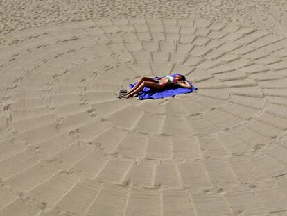 Una mujer toma el sol en una playa en Cannes, Francia.