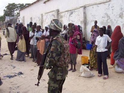 Un soldado de la Unión Africana en Somalia vigila a un grupo de somalíes.