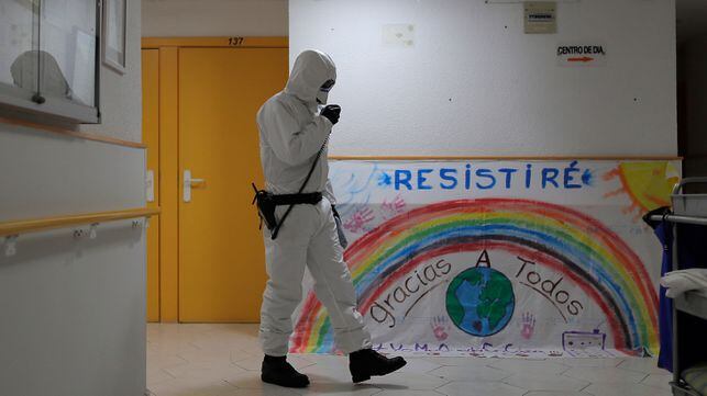 A member of the UME (Emergency Army Unit) wearing a wearing a protective suit to protect against coronavirus disinfects next to a banner reading in Spanish: "I will resist, Thanks everybody" at a nursing home in Madrid, Spain, Tuesday, March 31, 2020. The new coronavirus causes mild or moderate symptoms for most people, but for some, especially older adults and people with existing health problems, it can cause more severe illness or death. (AP Photo/Manu Fernandez)