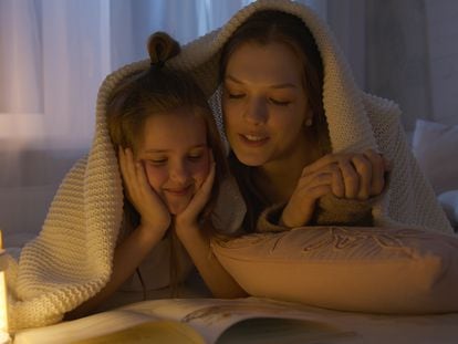 Una madre lee con su hija en la cama.