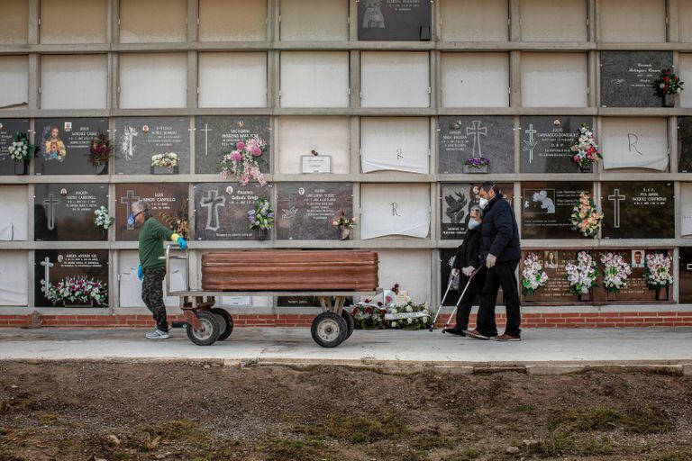 Un operario de un cementerio de Valencia traslada un féretro durante un entierro.