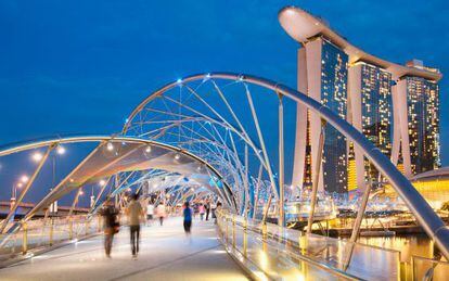 Paseantes en el puente Helix, en Singapur, con el famoso hotel Marina Bay Sands al fondo.