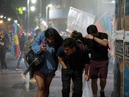 Un grupo de personas huye del cañón de agua utilizado por la policía antidisturbios de Chile, el pasado 17 de diciembre durante una protesta en Santiago.