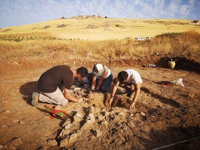 Tres arqueólogos excavan una del centenar de tumbas íberas halladas en la necrópolis de Alarcos. Al fondo, el castillo medieval.