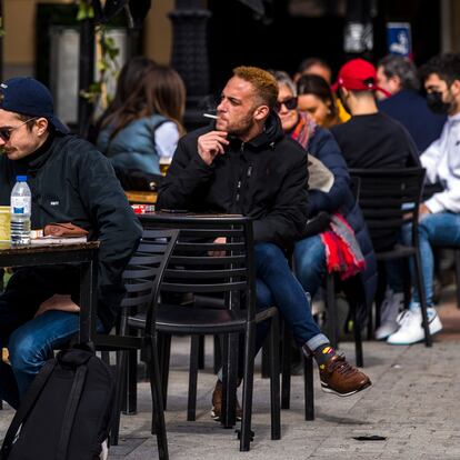 Una persona fumando en una terraza, en la plaza de Santa Ana de Madrid, el 18 de febrero.