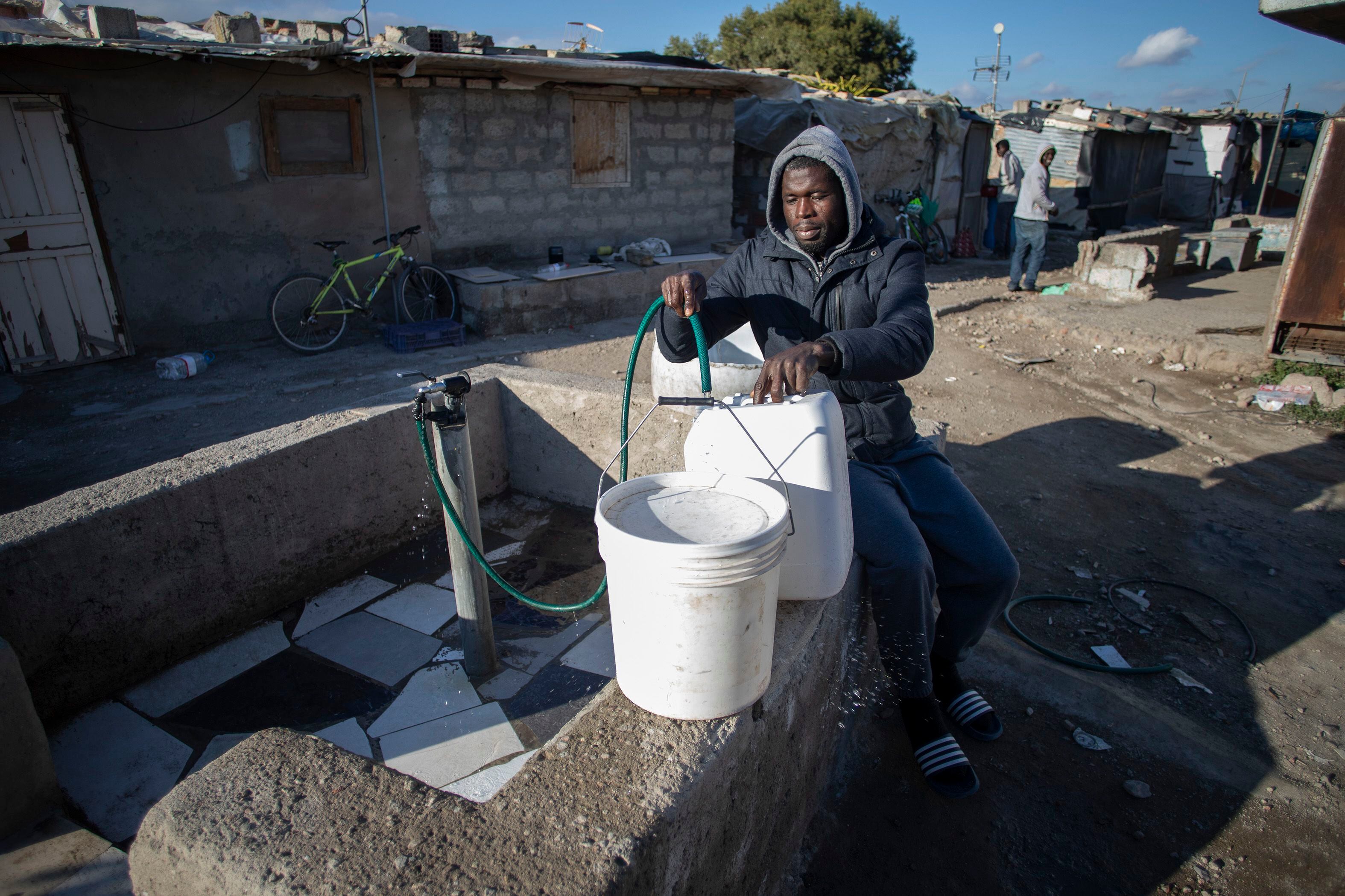 Un joven subsahariano se abastece de agua en una de las tres fuentes disponibles en el asentamiento de Atochares en Níjar (Almería). 