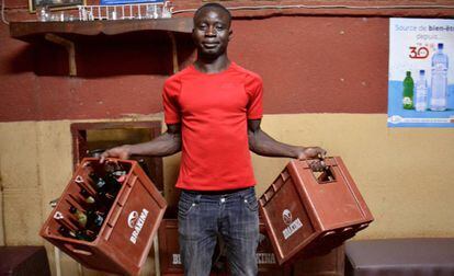 Adama Ilboudou coloca unas cajas de cerveza en el restaurante en el que trabaja.