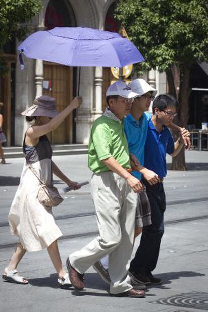 Un grupo de turistas pasea bajo el sol en Sevilla.