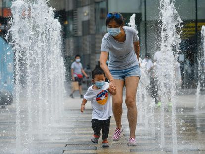 Una mujer y un niño pasean con mascarilla por un centro comercial de Pekín.