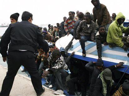 Un policía libio ayuda a desembarcar a unos inmigrantes rescatados tras llegar a Trípoli el domingo.