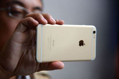 Un hombre sujeta un iPhone 6, un teléfono de Apple.
