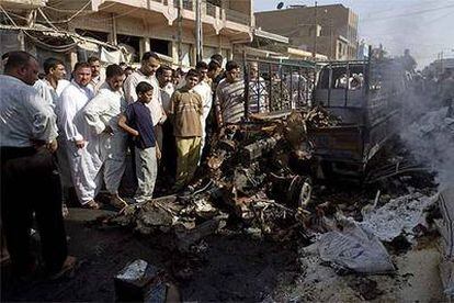 Varios iraquíes miran los restos de uno de los coches bomba que explotó en Balad el pasado jueves.