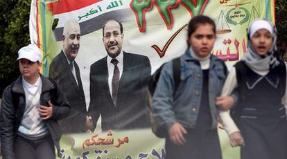 Escolares iraquíes pasan ante un cartel electoral del partido del primer ministro, Nuri al Maliki, en el centro de Bagdad.