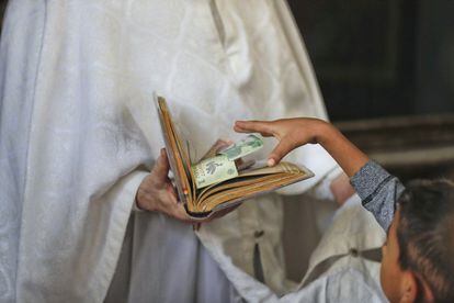 Un niño mete dinero en un libro religioso, en Costesti.
