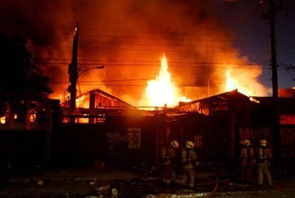 Los bomberos tratan de apagar el fuego en un almacén incendiado durante los disturbios en Chile.