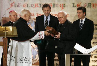 El de&aacute;n de la Catedral recibe el C&oacute;dice de manos del arzobispo, ante la mirada de Rajoy y Feij&oacute;o. / ANXO IGLESIAS