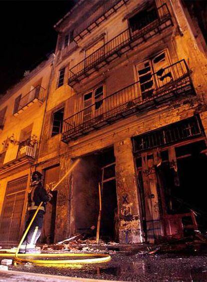 Un bombero lanza agua sobre la fachada de un edificio situado en el casco antiguo de Valencia, donde ha ardido el antiguo Teatro Princesa.