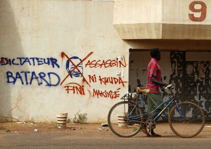 OUAGADOUGOU (BURKINA FASO), 06/11/2014.- Un hombre camina junto a una pintada en contra del presidente Blaise Campaoré en las calles de Ouagadougou, Burkina Faso hoy 6 de noviembre de 2014. Burkina Faso ha superado la crisis social y política iniciada con el derrocamiento popular del presidente Blaise Campaoré al lograr un acuerdo para establecer un Gobierno civil de transición hasta las próximas elecciones generales, que se celebrarán en 2015. EFE/Legnan Koula