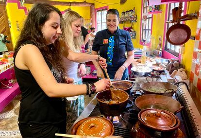 La chef Alejandra Treviño supervisa la preparación del menú con dos visitantes, en su escuela de Puerto Morelos (México).