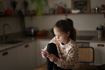 Una niña se entretiene con su teléfono móvil.