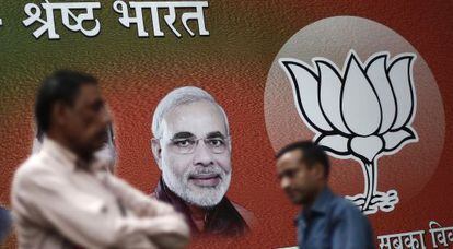 Varios hombres pasean frente a un cartel del candidato hindú, Narendra Modi.