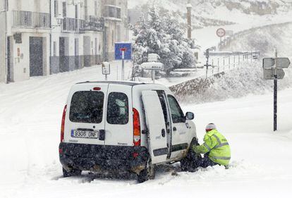 Un hombre intenta poner las cadenas a su coche en Coll D'ares a unos 1.100 metros de altitud. La provincia de Castellón está en alerta roja por la intensidad de las nevadas caídas a lo largo del día.