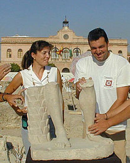 Dos miembros de la excavación arqueológica posan junto a los restos de la escultura romana hallada en Écija.