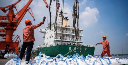 Trabajadores descargan productos químicos en el puerto chino de Zhangjiagang.
 